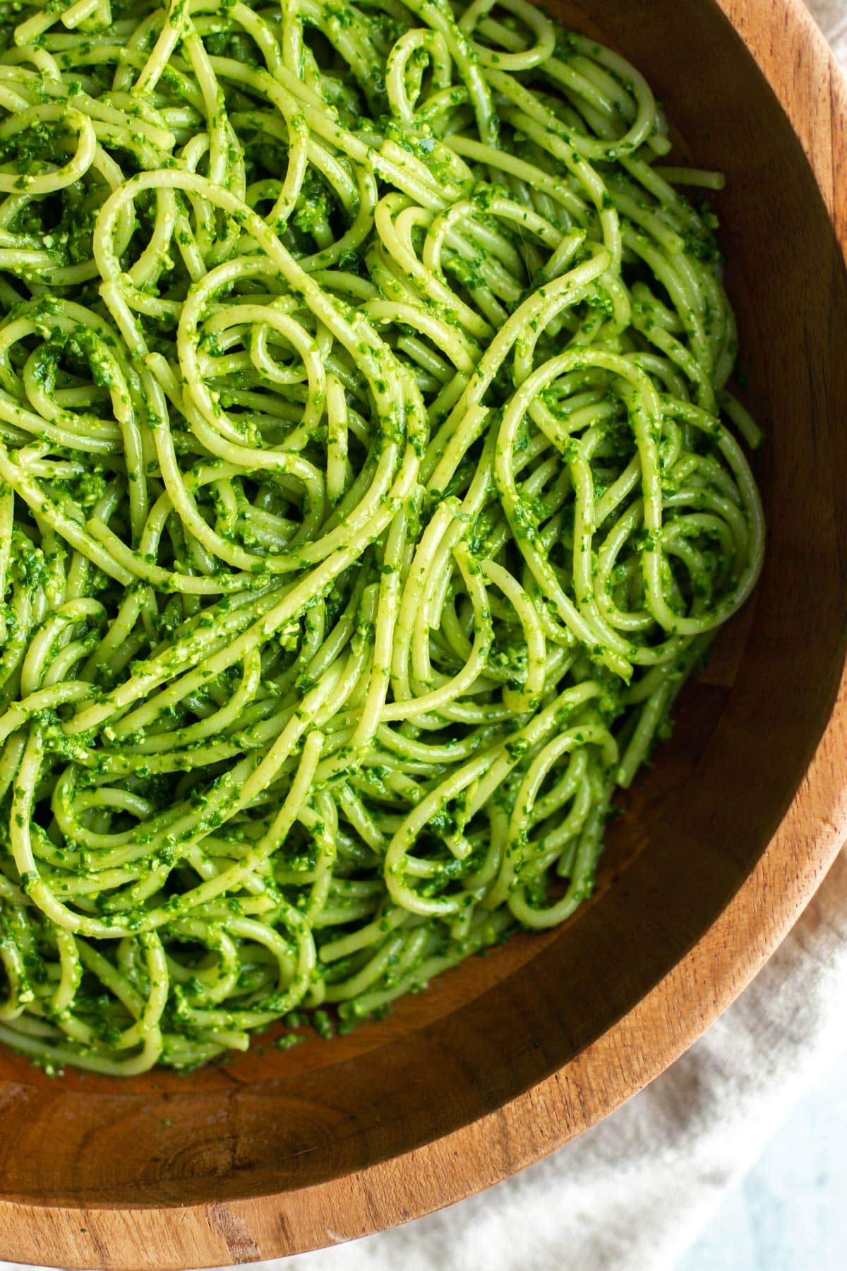 pasta tossed with pesto in a wooden bowl.