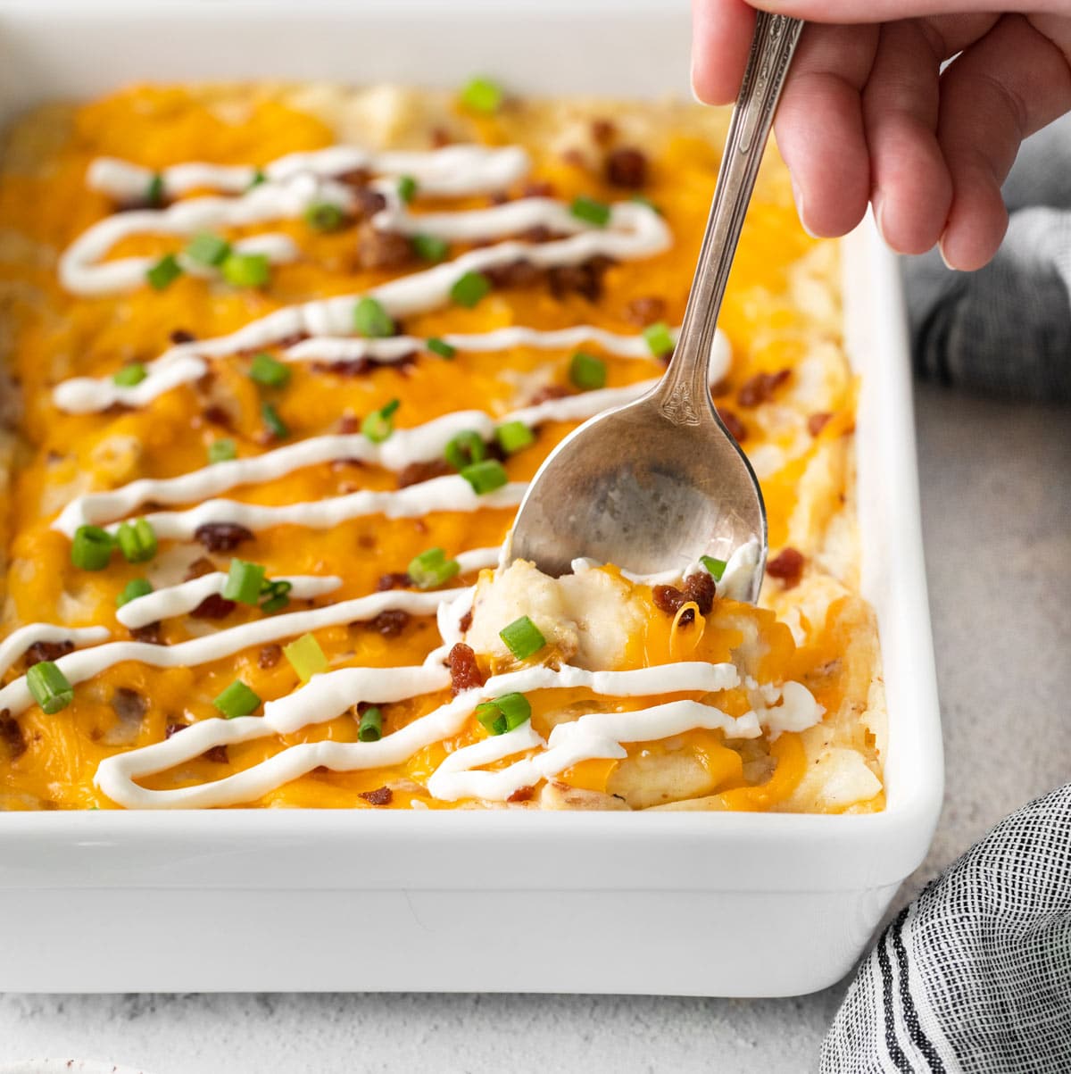 a spoon scooping out some of the potato casserole.