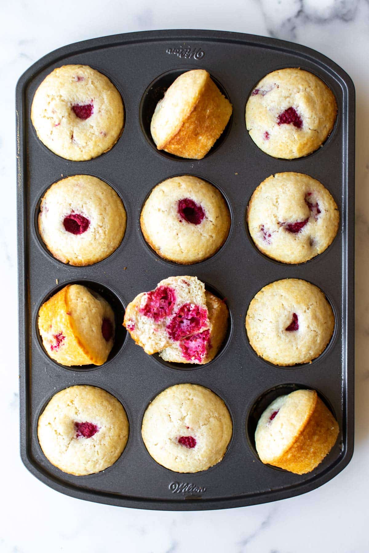 baked raspberry muffins in a muffin pan.