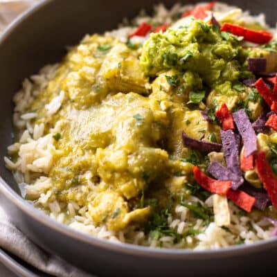salsa verde chicken on rice with guacamole and tortilla strips.
