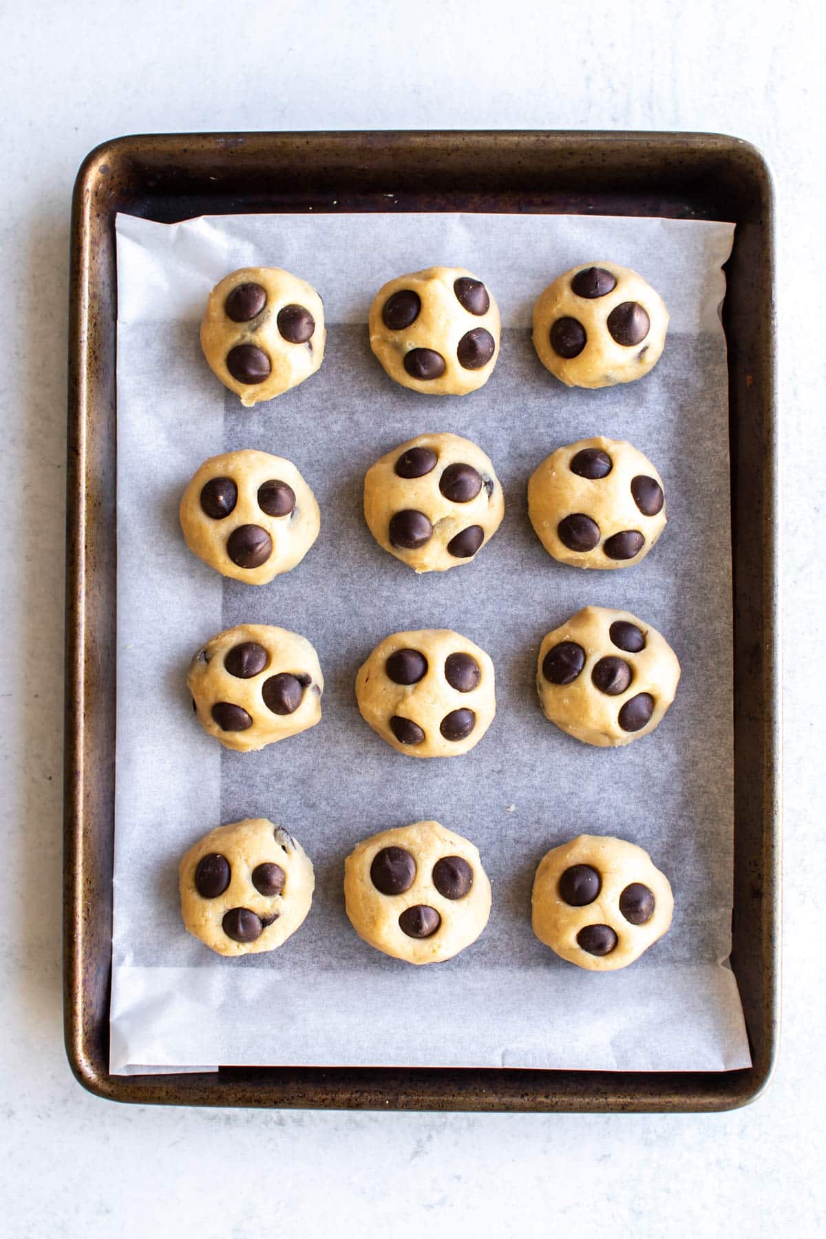 cookie dough balls on a sheet pan lined with parchment.