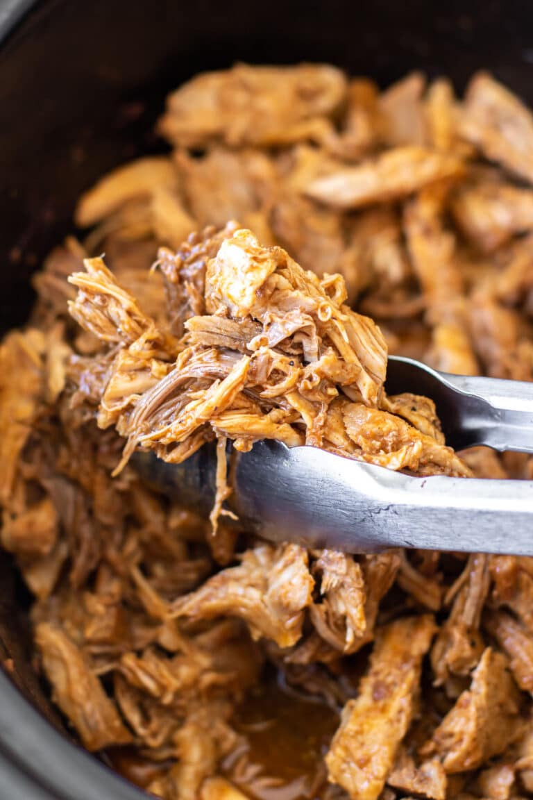 tongs holding some shredded pork.