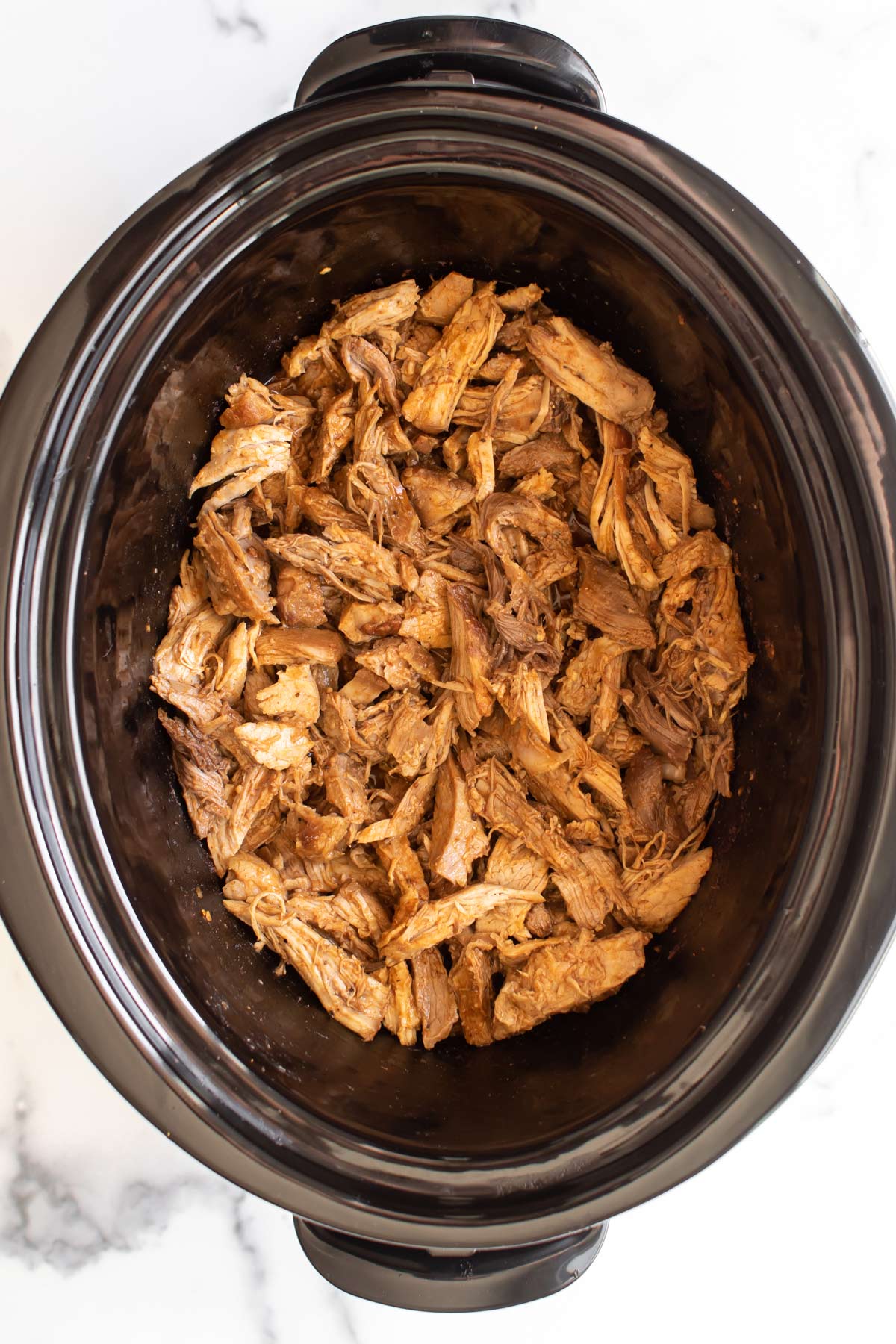 the pork after it's been shredded in the slow cooker.