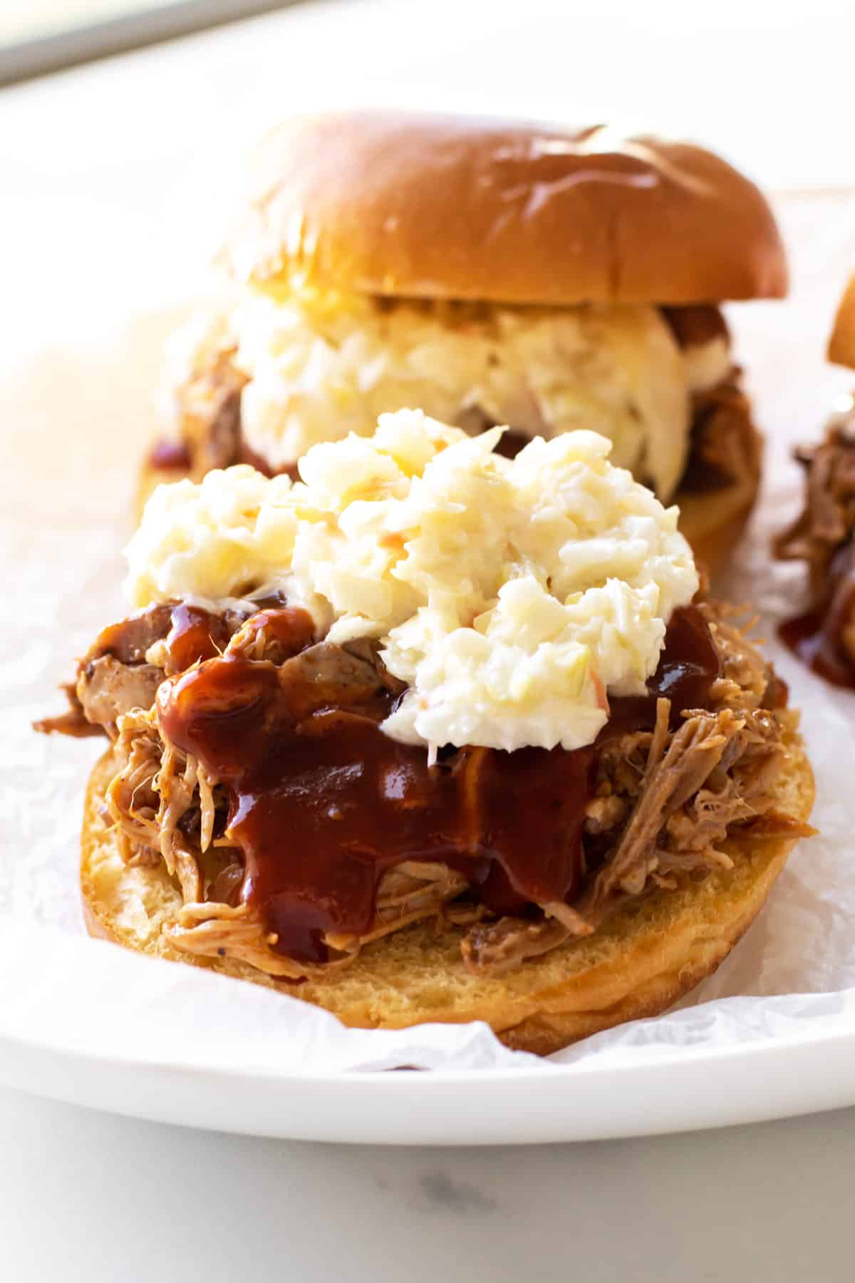 a open faced sandwich topped with BBQ sauce and coleslaw.
