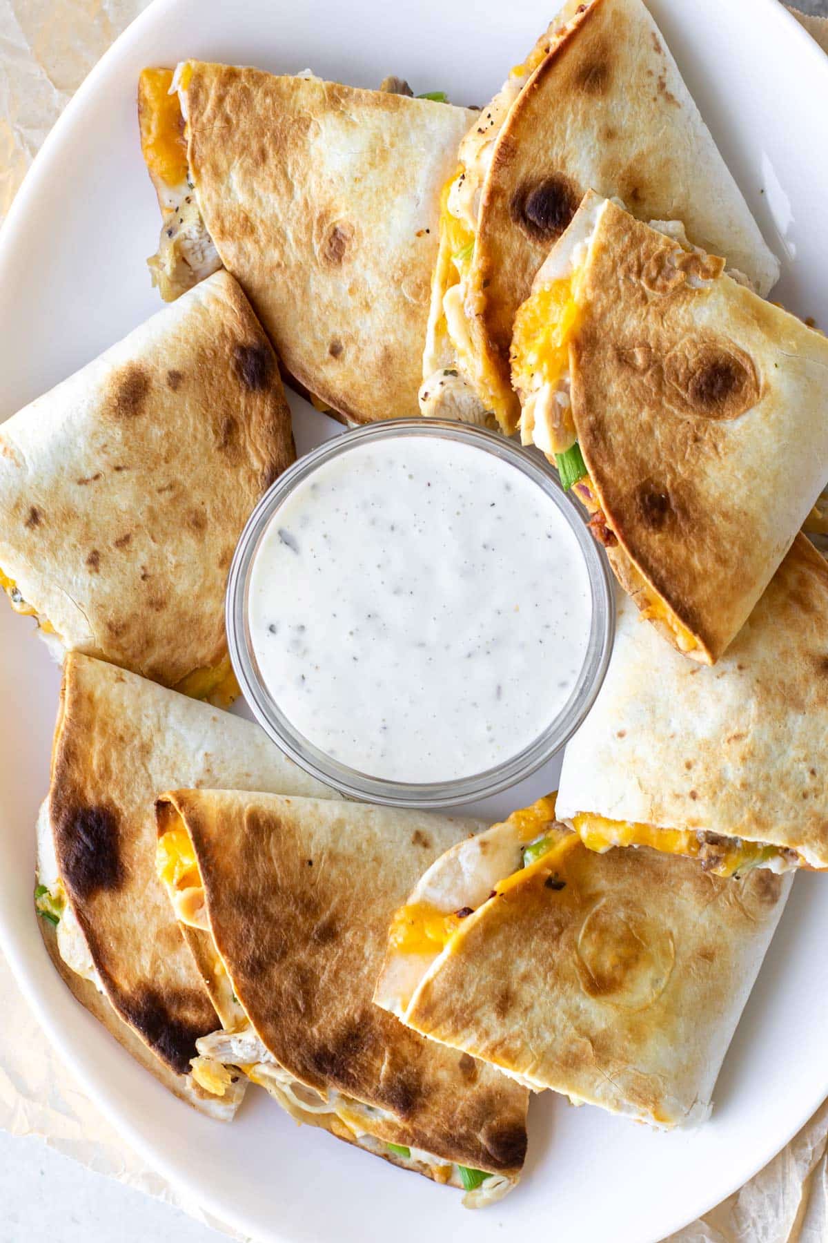 sliced chicken quesadillas on a plate with ranch dressing.