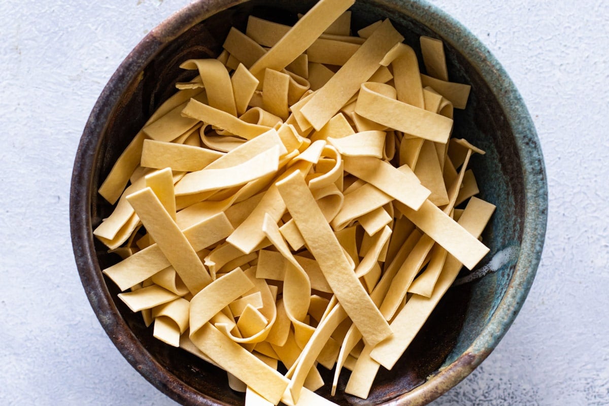a bowl of uncooked thick egg noodles.