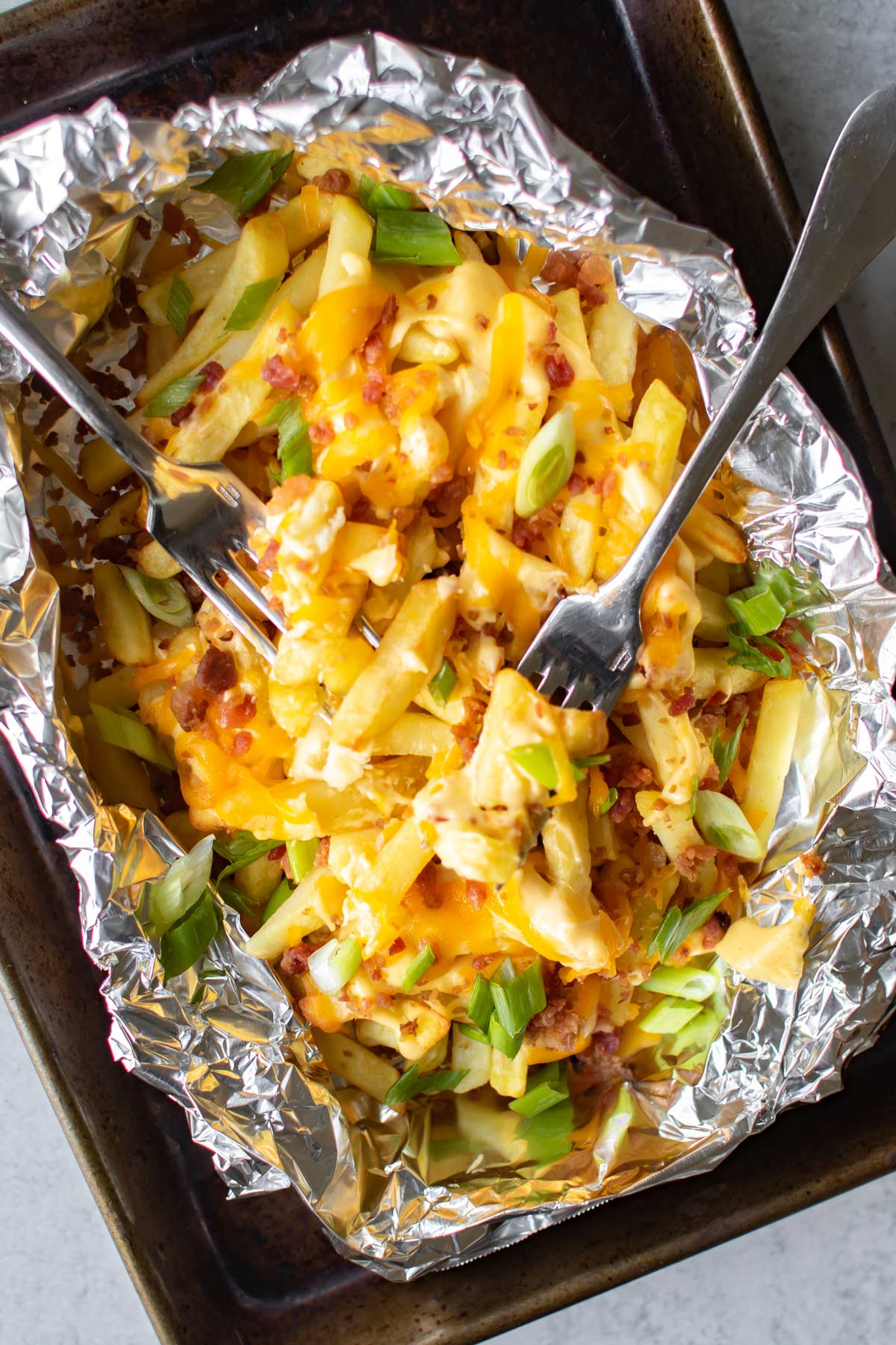 cheese fries in foil with two forks.