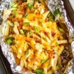 loaded cheese fries in foil on sheet pan.