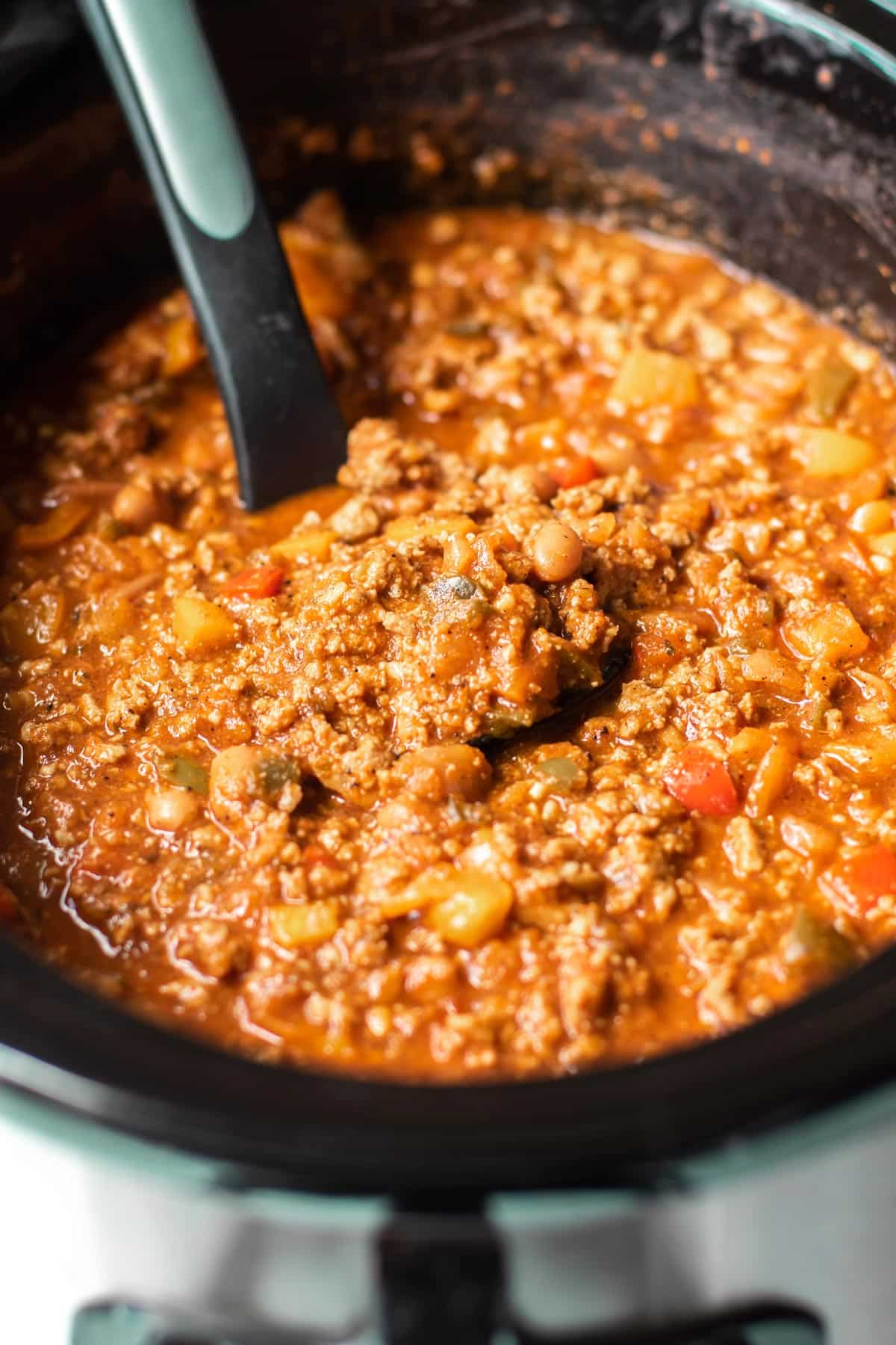 a ladle in a slow cooker with turkey chili.