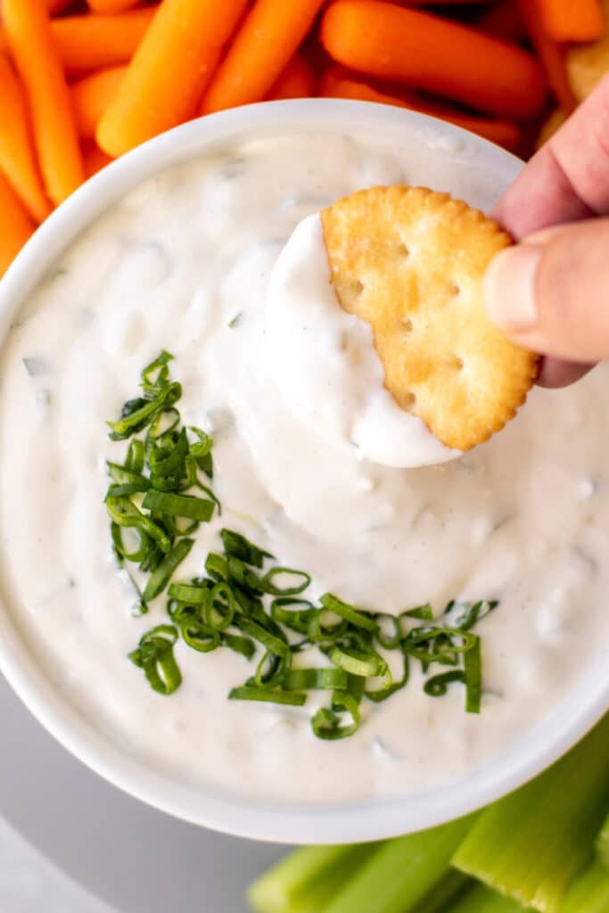 a cracker being dipped in the the dip.