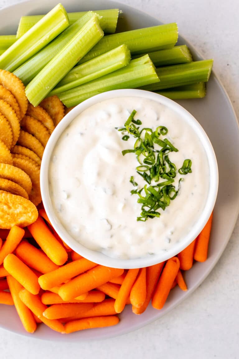 a bowl of dip with carrots, celery, and crackers on the side.