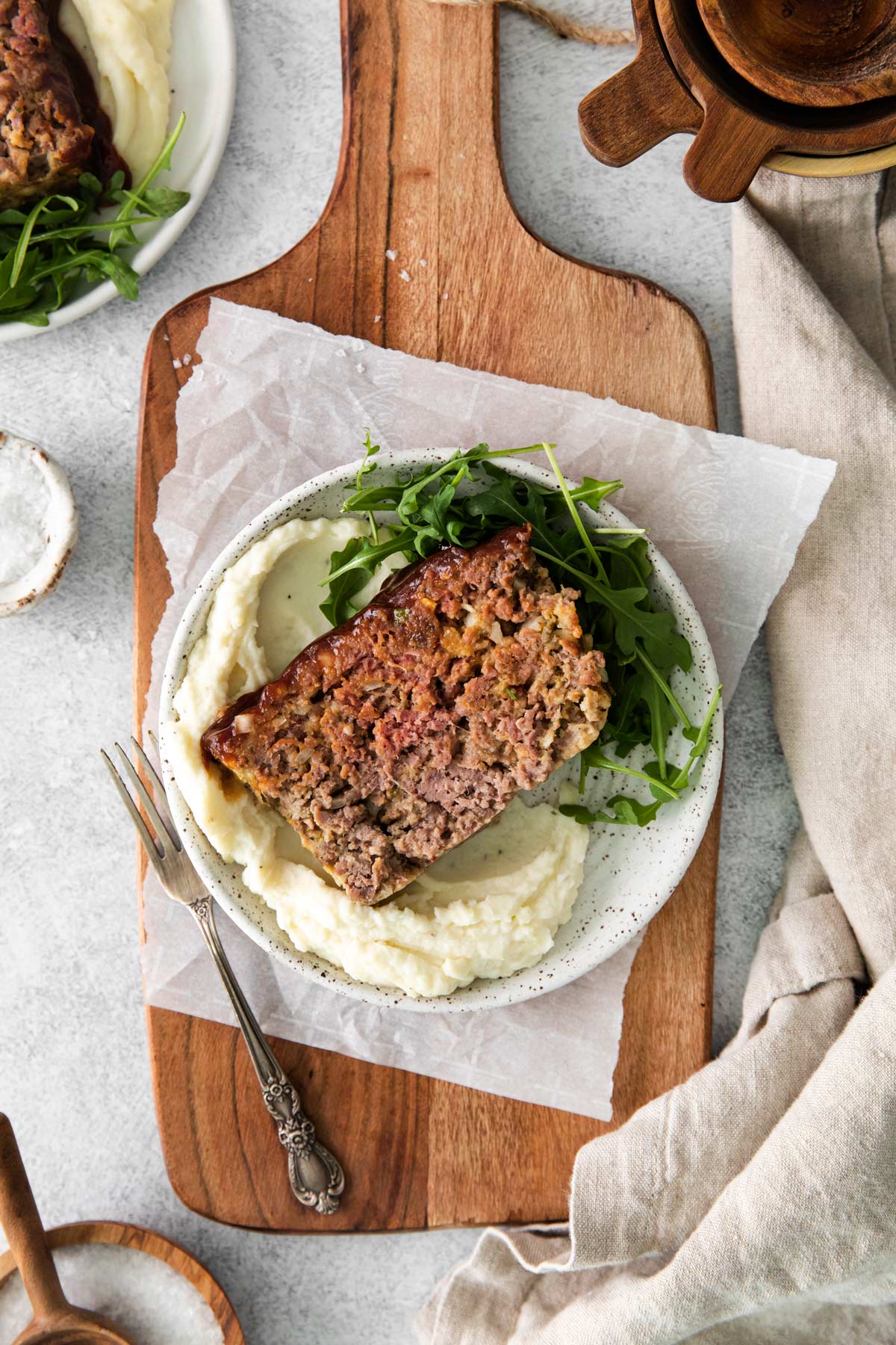 a slice of meatloaf on a plate with mashed potatoes and greens.
