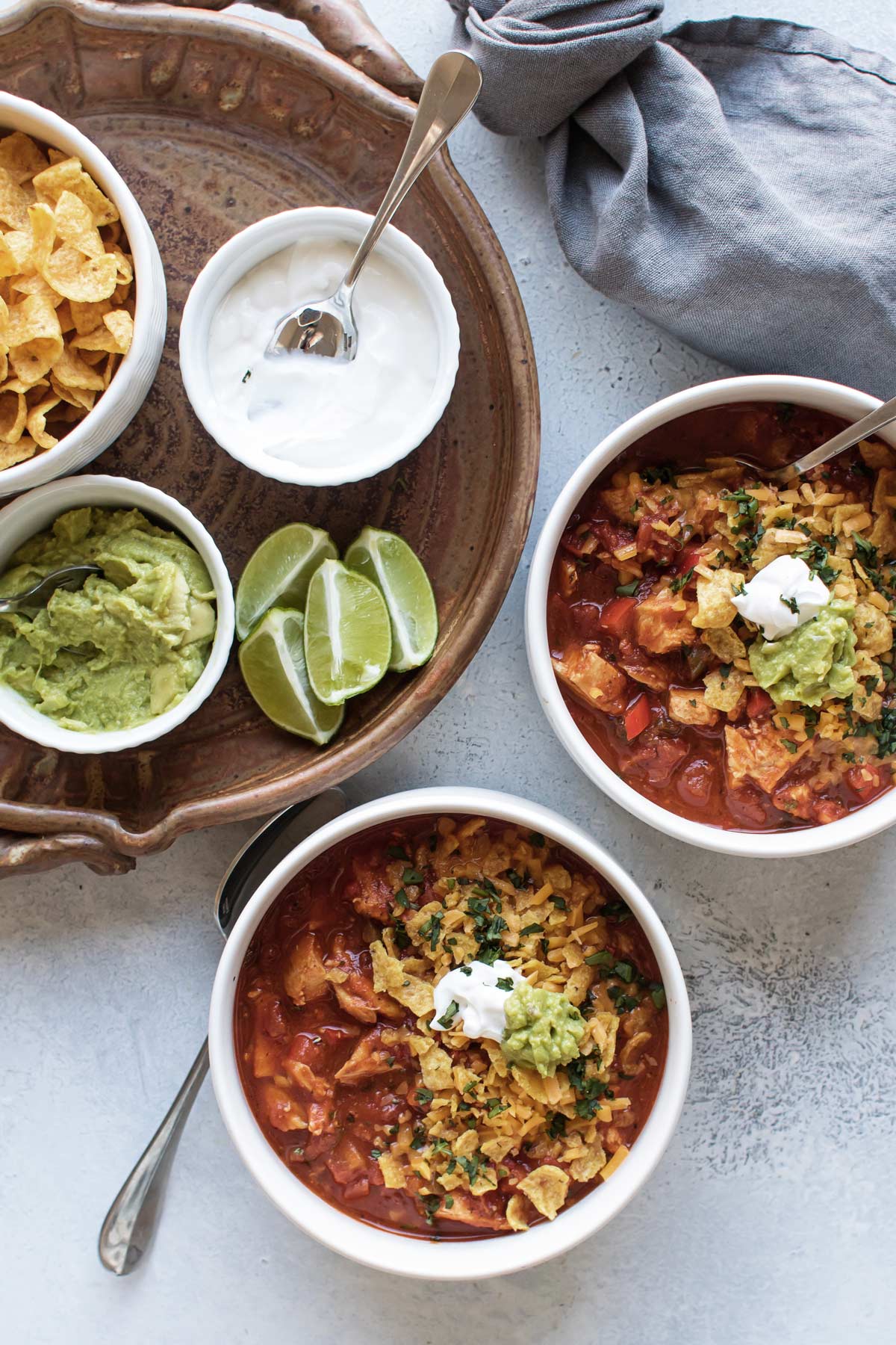 two bowls of chili with toppings on the side.