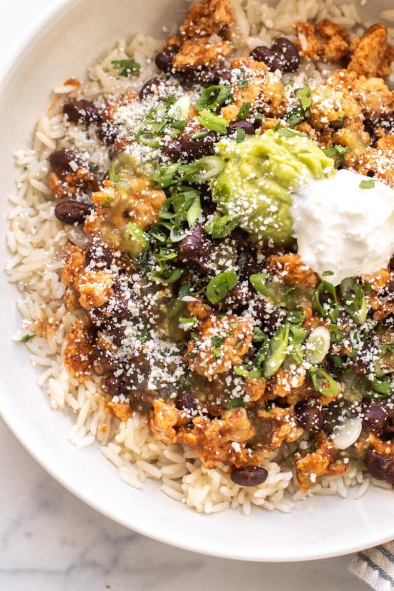 rice topped with taco chicken meat, beans, and garnishes.