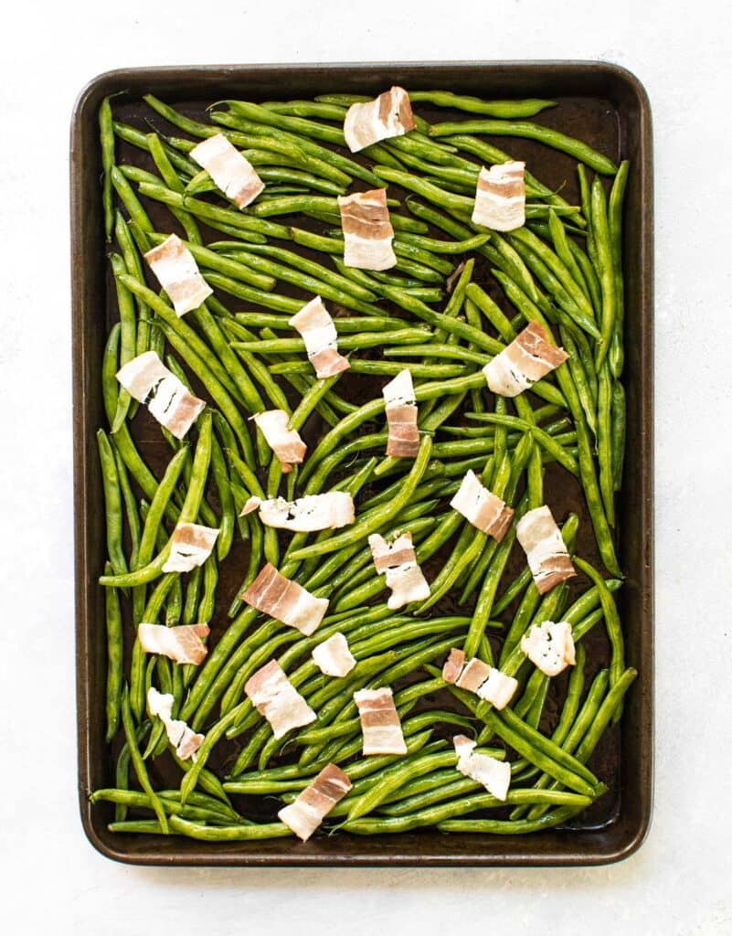 green beans and bacon on a sheet pan ready to go in the oven.