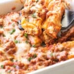 two stuffed manicotti being lifted from the pan.