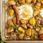 sheet pan potatoes and sausage with a cooked egg on a sheet pan.