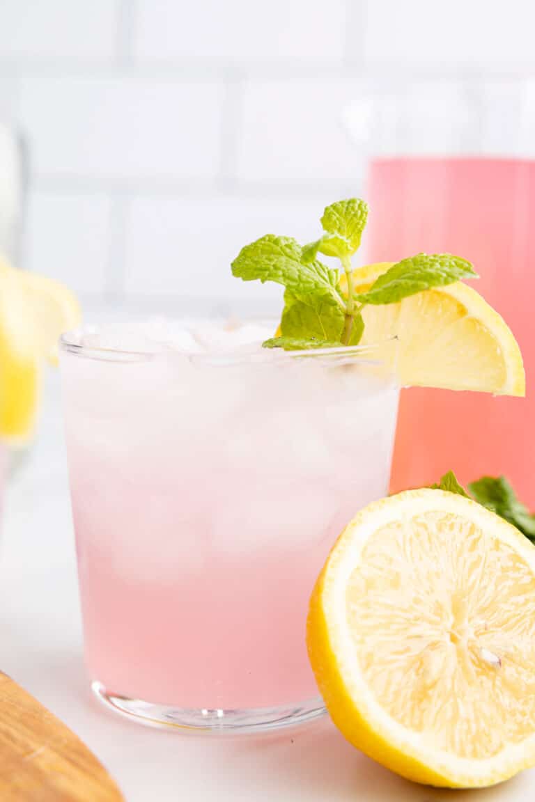 a pink margarita garnished with mint and lemon.