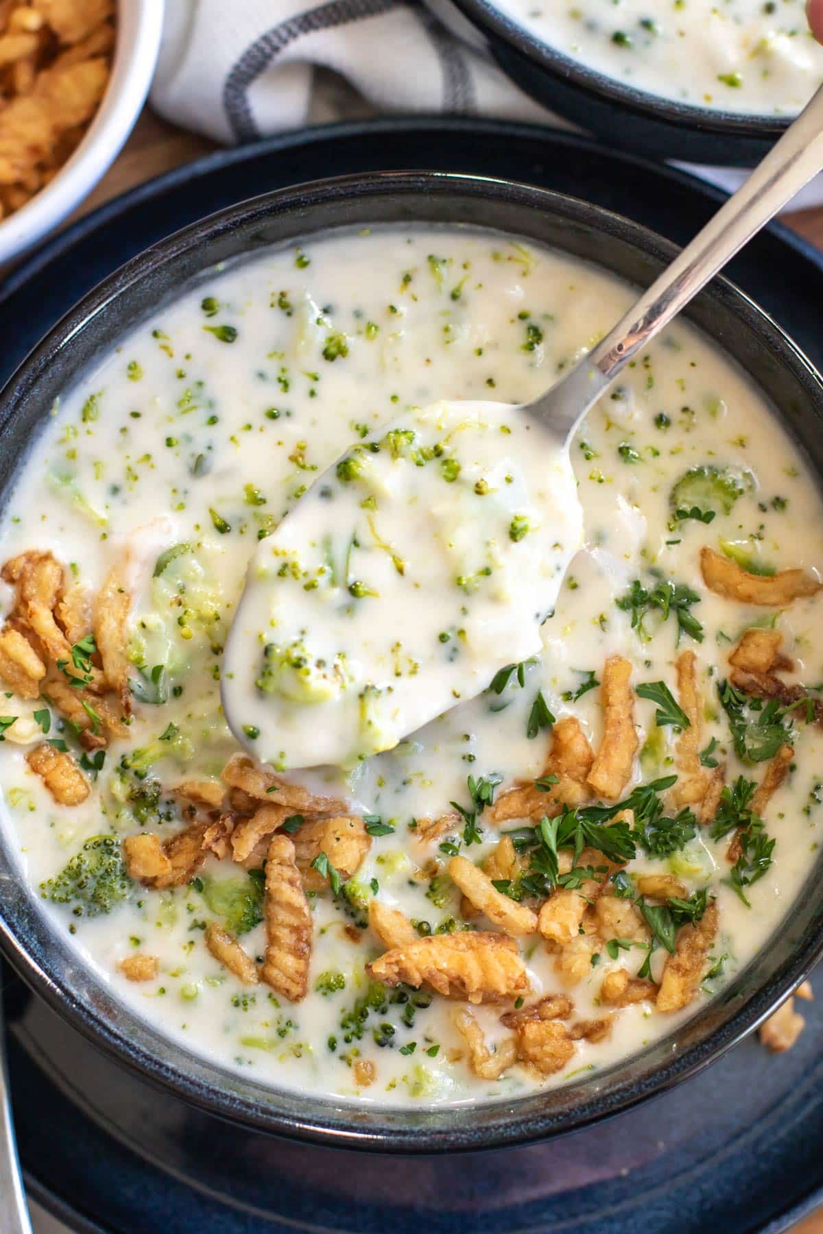 a spoonful of soup over a bowl of soup.