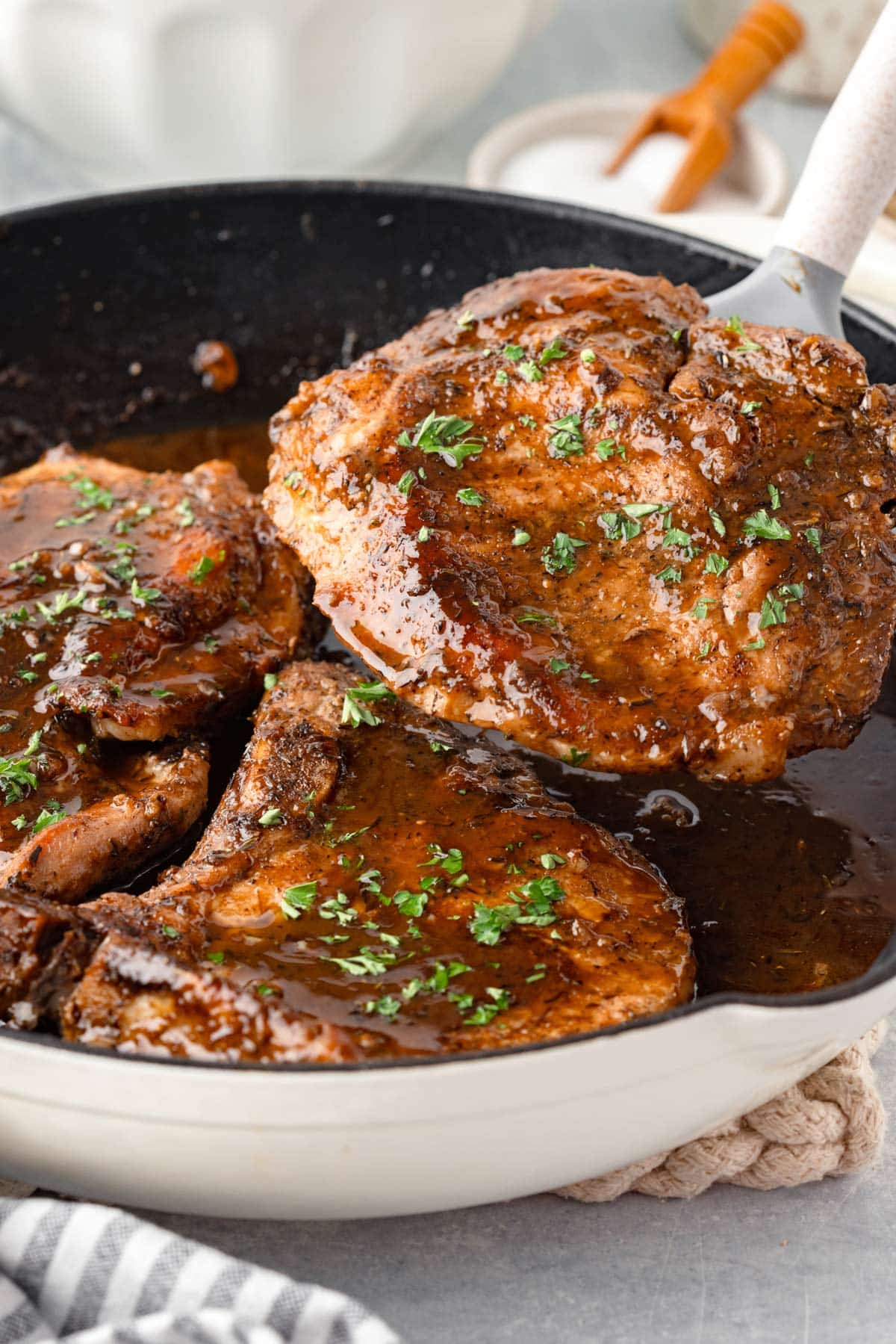 a pork chop being lifted from the pan.