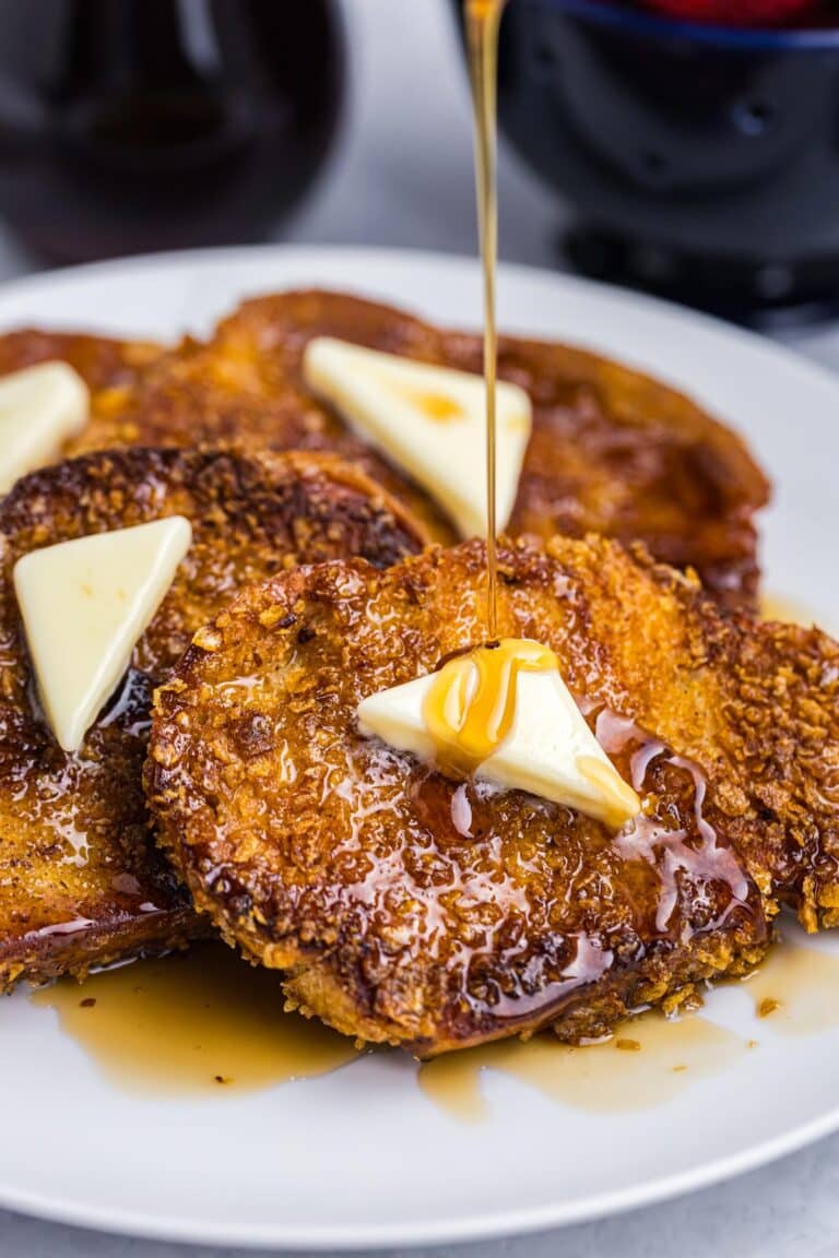 a plate of french toast being drizzled with syrup.