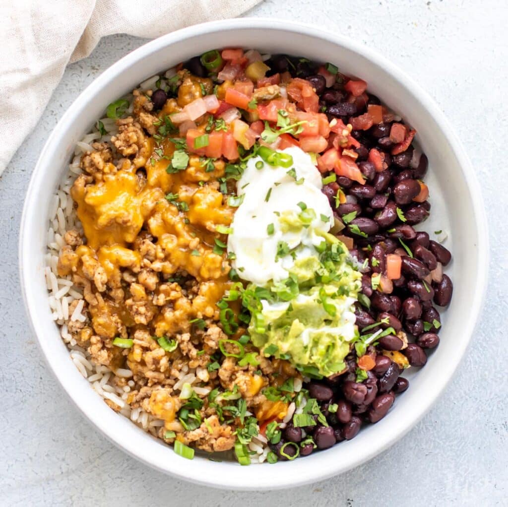 ground pork verde enchilada bowl with sour cream and guacamole.