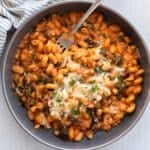a bowl of white bean spinach pasta with cheese on top.