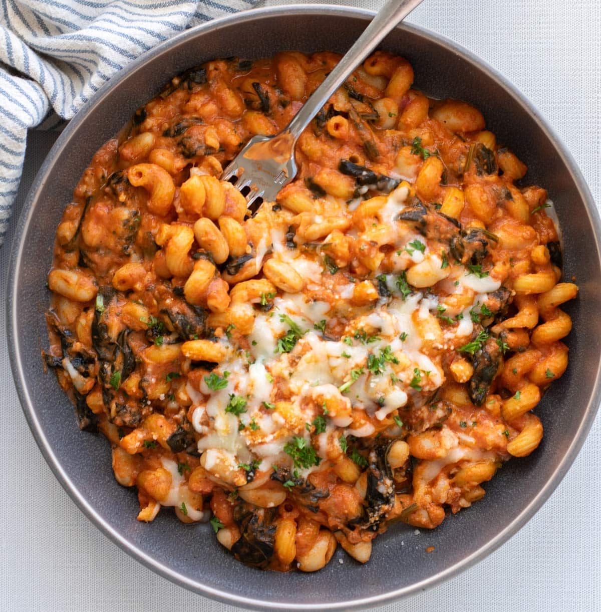 a bowl of white bean spinach pasta with cheese on top.