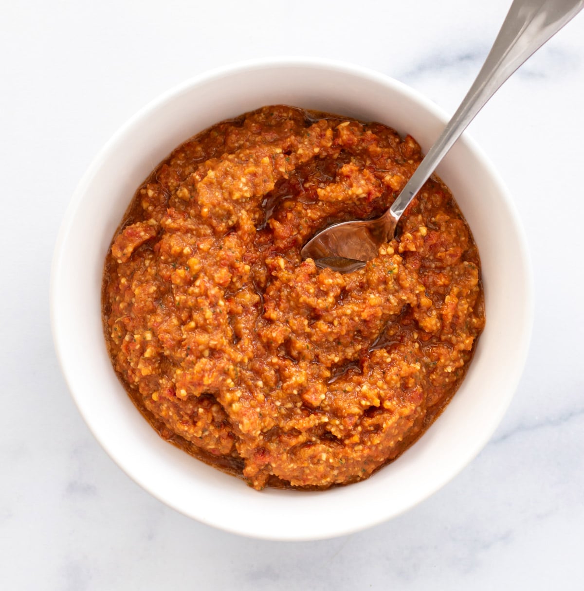 a bowl of pesto with a spoon.