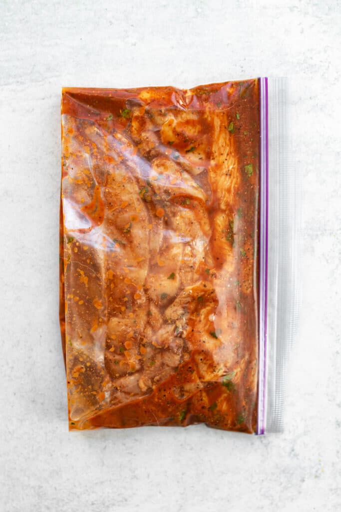 chicken marinating in a ziplock bag.