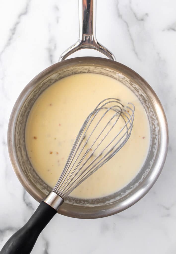 the cheese sauce in a pan with a whisk.