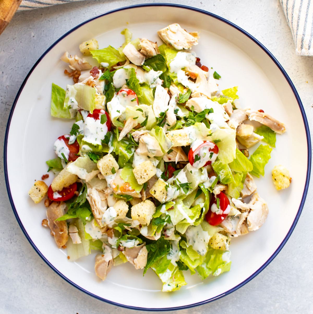 club chopped salad on a white plate with a blue rim.