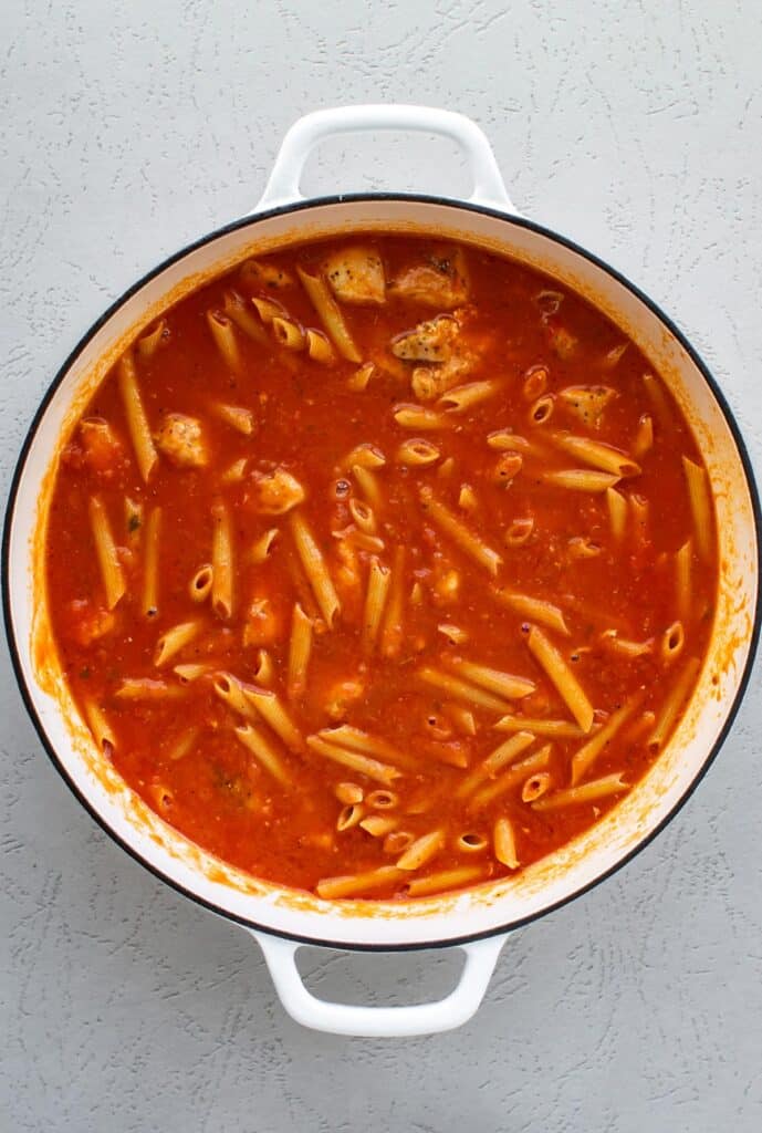 the sauce, water, and pasta added to the pan.