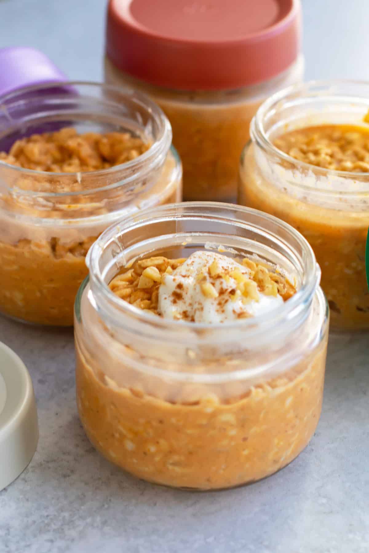 a container of overnight oats topped with a little yogurt and chopped walnuts.