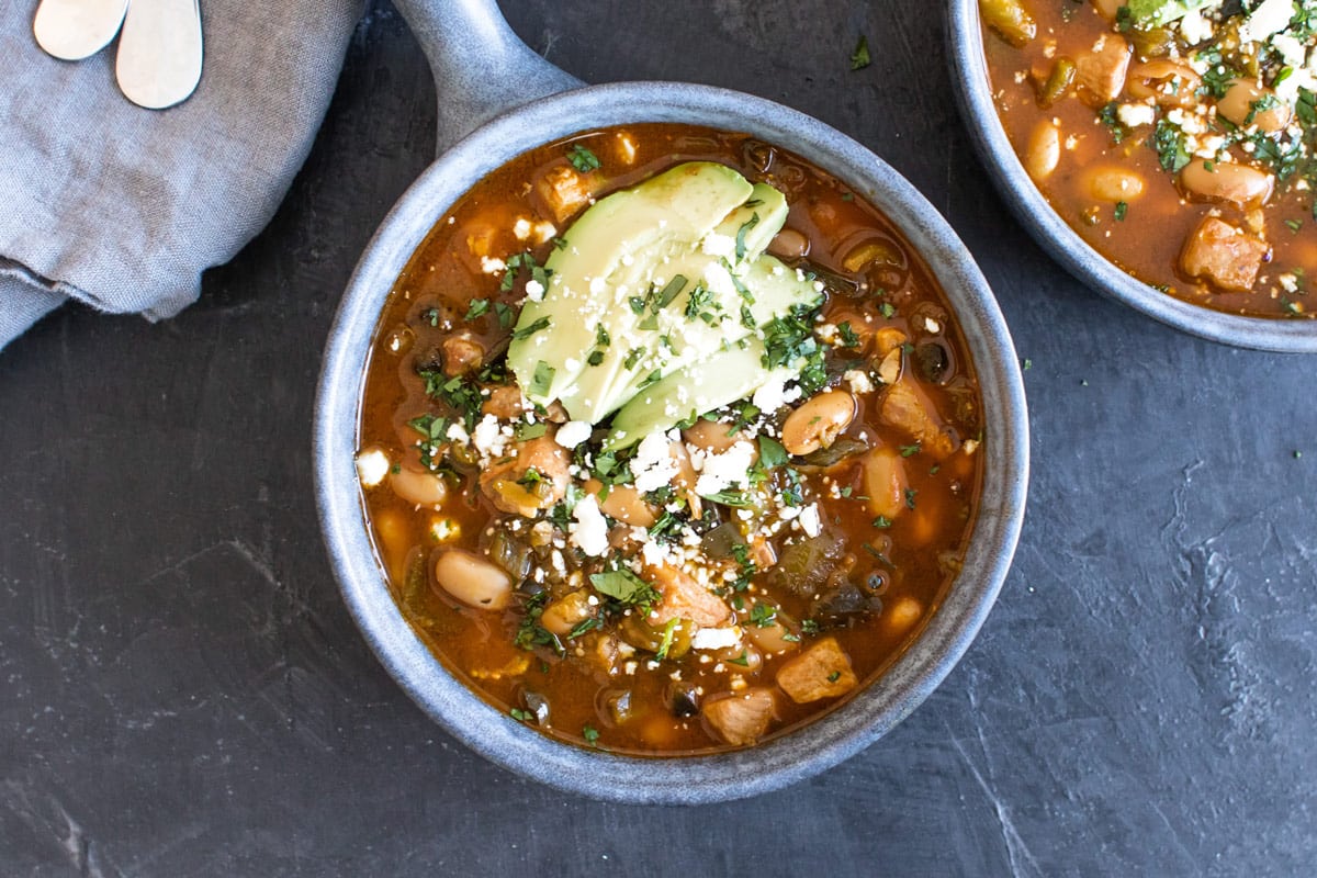a bowl of chili with cheese and avocado.