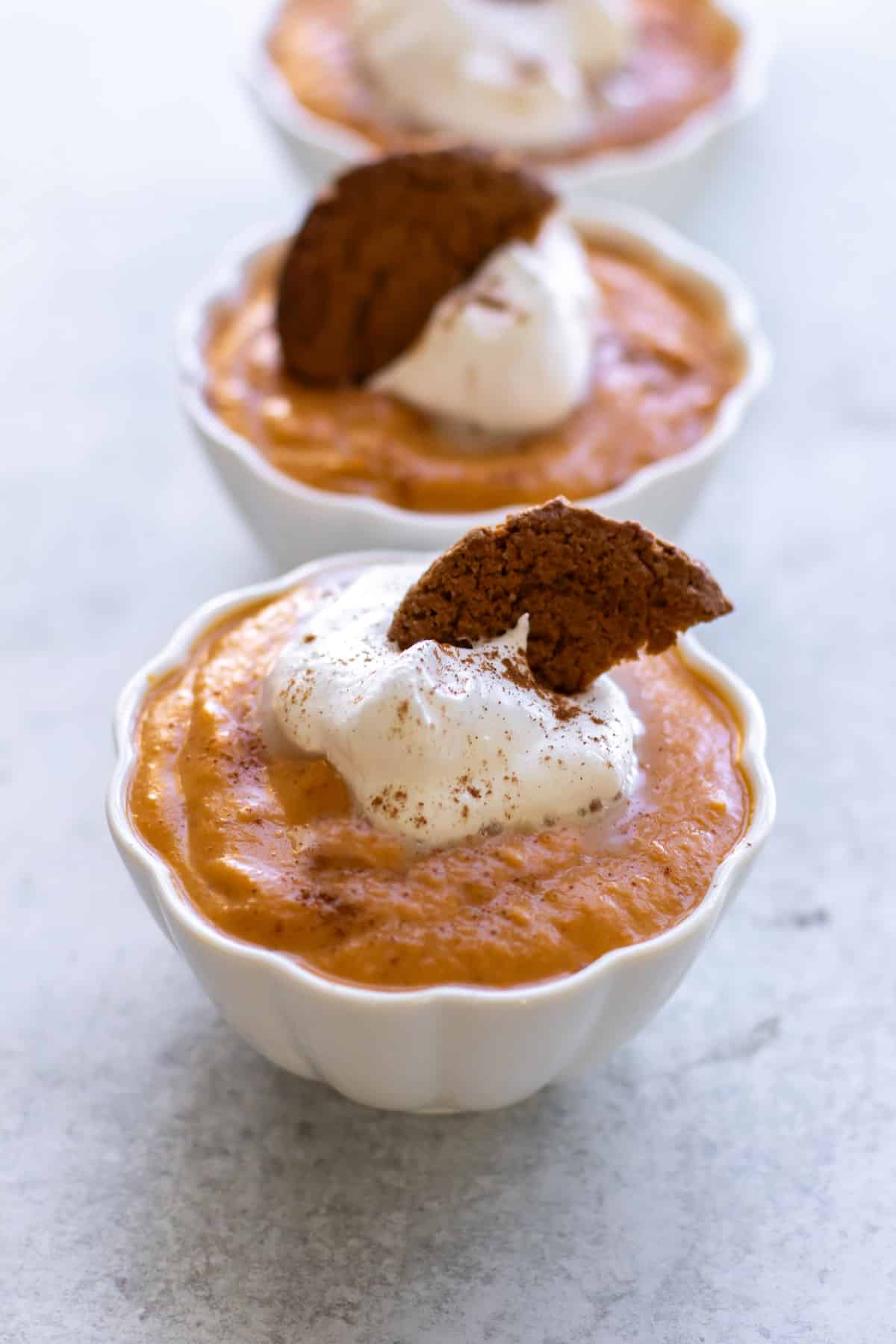 a bowl of pudding topped with whipped cream and a gingersnap.