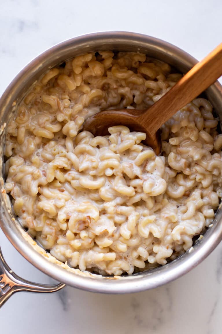 a pan of macaroni and cheese with a wooden spoon.
