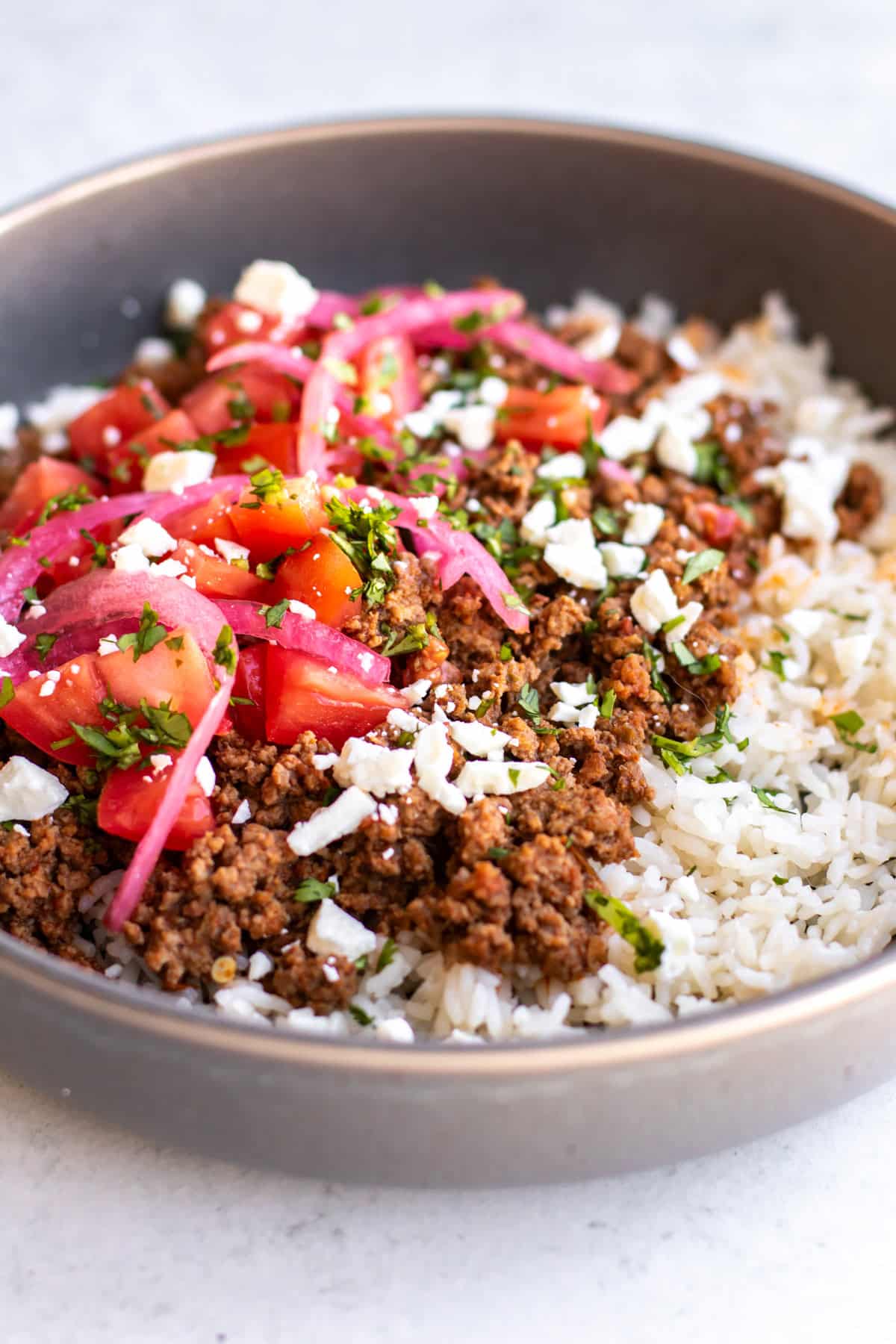 a bowl of chorizo beef with rice and garnishes.