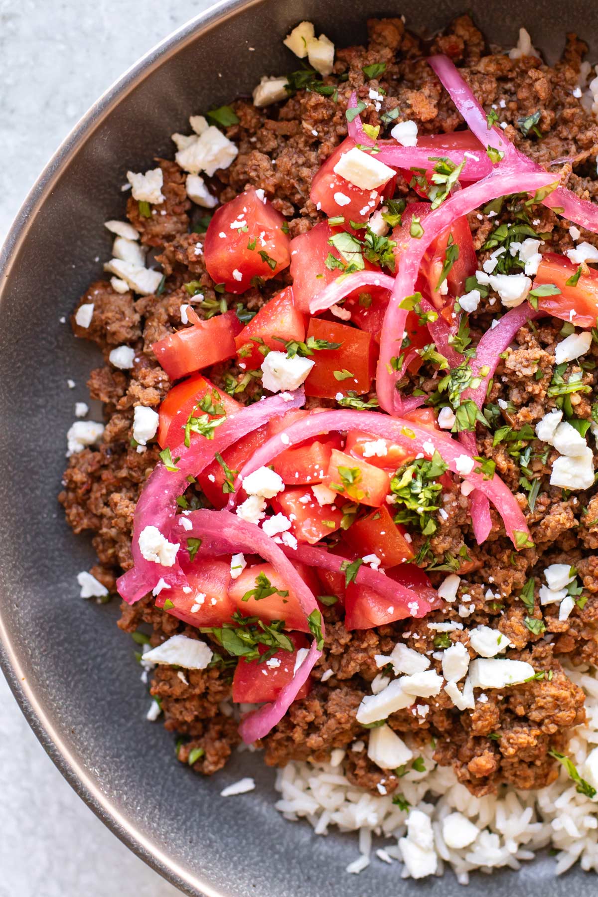 the tomatoes, onions, and feta cheese added to the bowls.