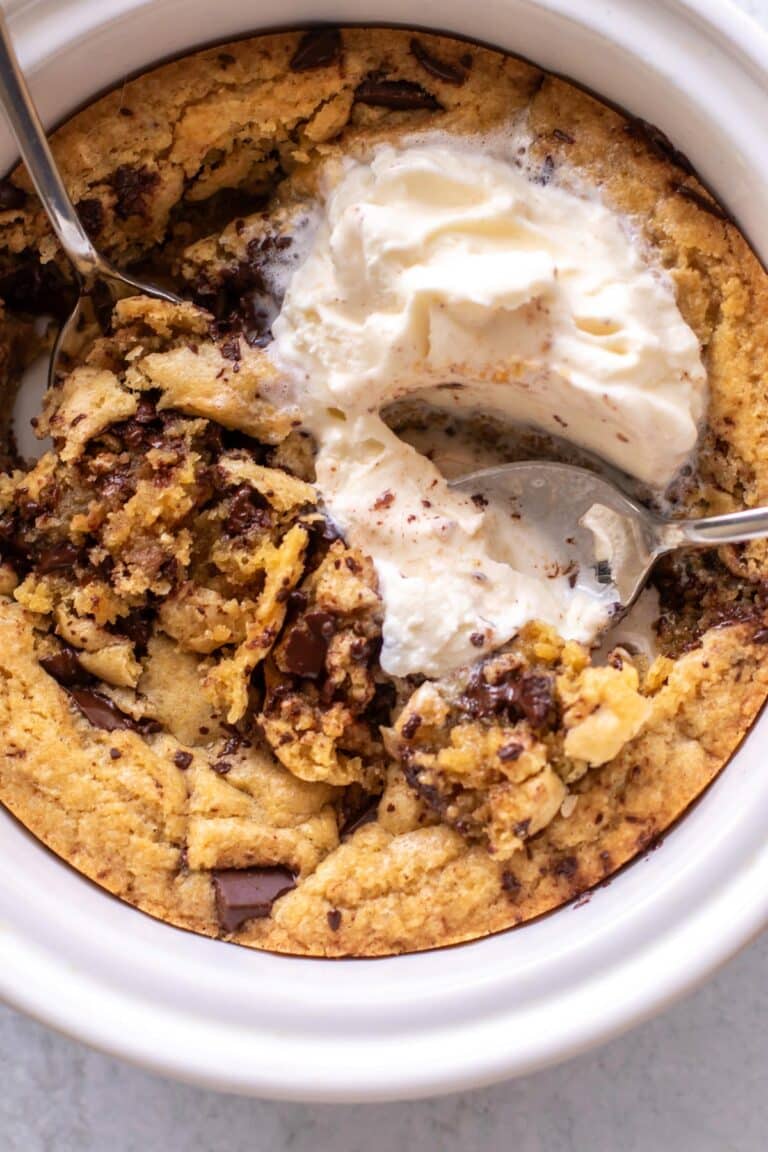 a deep dish cookie with ice cream and two spoons.