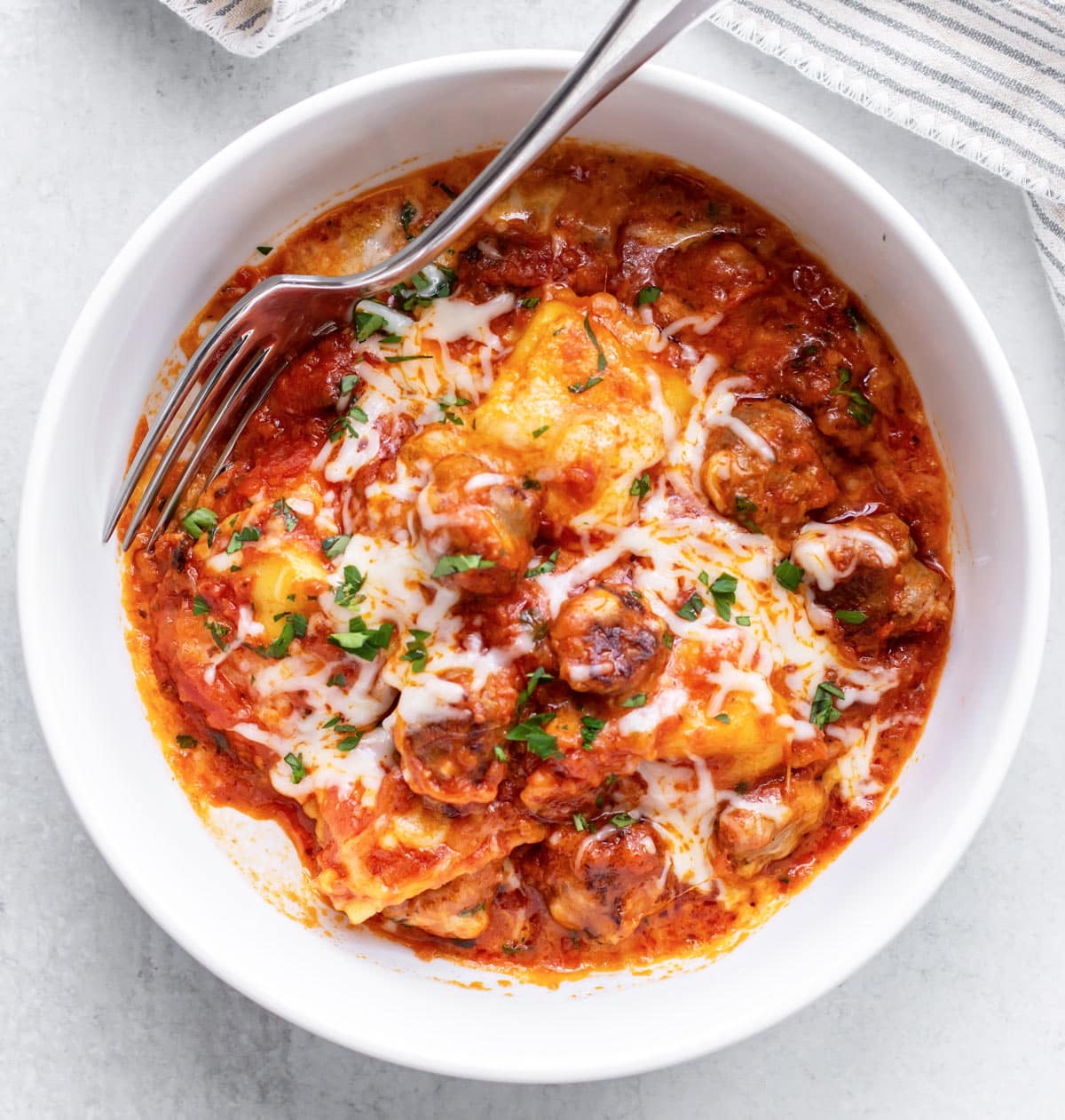 a bowl of sausage ravioli with sauce and cheese.