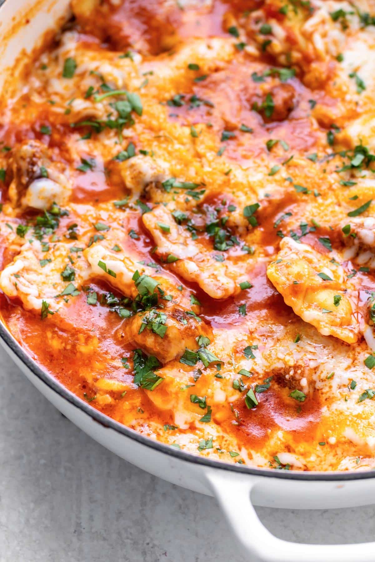 a pan of sausage ravioli topped with melted cheese.