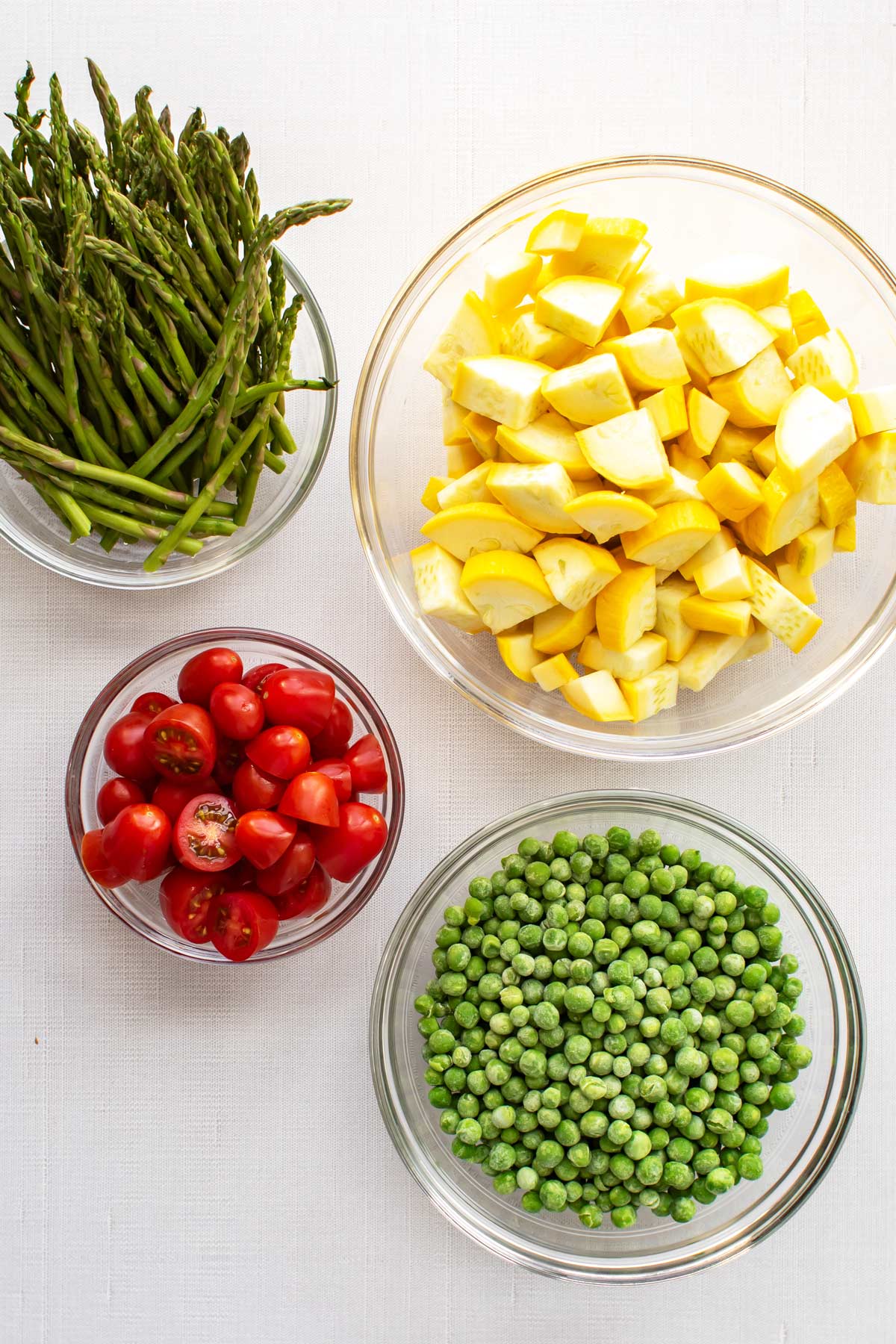 the asparagus, squash, tomatoes, and peas in separate bowls